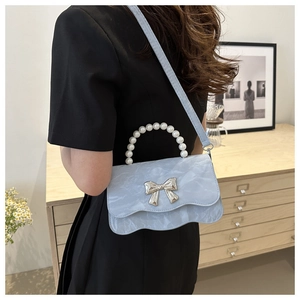 Detail of light blue crossbody bag with pearl handle and silver bow buckle for women