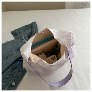 Detail view of white textured tote bag interior showing large capacity and purple strap