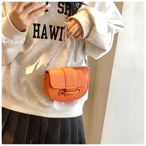 Close-up of orange saddle bag with pebble leather texture and silver ball chain strap