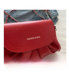 Détail du sac nuage plissé rouge avec logo argenté et bandoulière en chaîne métallique