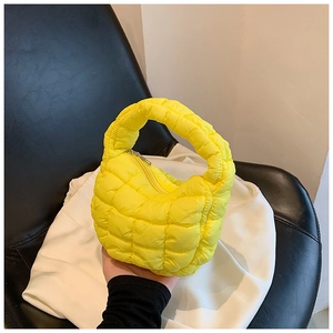 Detailed close-up of a bright yellow quilted cloud bag featuring a soft puffy square pattern