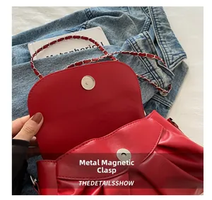 Détail du fermoir magnétique en métal du sac en cuir rouge avec bandoulière en chaîne