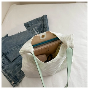 Close-up of beige tote bag with green strap showing spacious interior and texture