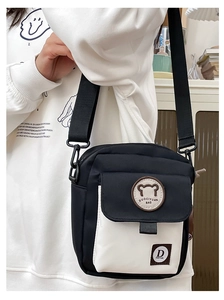 Detail view of black and white canvas crossbody bag with cute bear patch and nylon strap