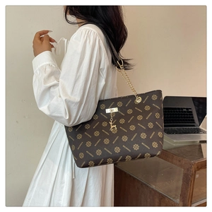Detail der braunen Monogramm-Tasche mit goldenem Hirschanhänger und Kettenriemen
