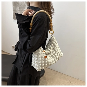 Detail of white bubble texture tote bag with wooden bead strap shown on a female model