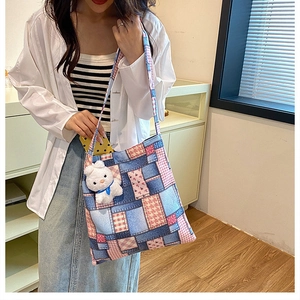 Detailed close-up of a multi-pattern patchwork canvas tote bag with a plush rabbit charm