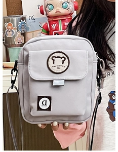 Detail view of the light grey canvas messenger bag with cute bear patch and flap pocket