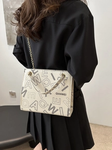 Fashionable cream shoulder bag with black letter prints and elegant gold chain strap
