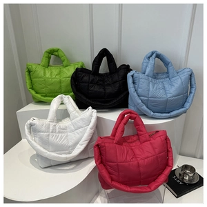 Quilted down puffer tote bags displayed in multiple colors on a white tiered platform