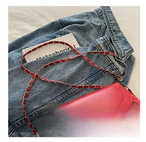 Détail d'un sac bandoulière rouge plissé avec chaîne argentée sur veste en jean