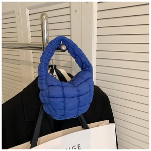 Detail of quilted bright blue puff cloud handbag with ruched fabric texture