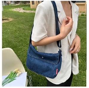 Detail view of denim crossbody bag with metal snap button and vintage texture