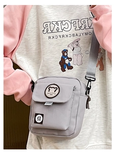 Close-up of light grey canvas crossbody bag with cute bear embroidery and adjustable strap