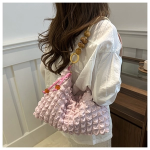 Detail of light pink popcorn texture shoulder bag with decorative beaded wooden strap