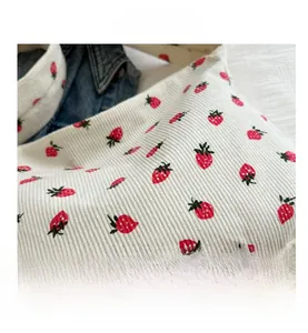 Gros plan sur le tissu en velours côtelé beige avec broderie fraise rouge