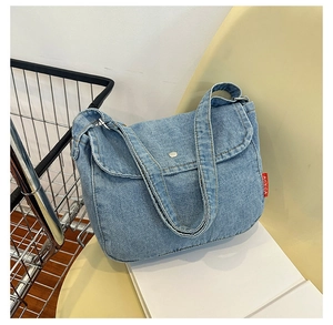Detail of light blue denim tote bag with red brand label and magnetic closure detail