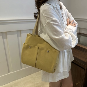 Minimalist bright yellow canvas tote bag with dual front pockets for women's daily commute