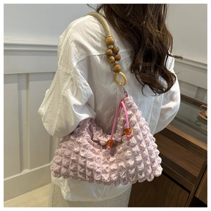 Detail of lavender bubble textured shoulder bag with wooden bead handle and drawstring closure