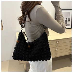 Detail of black pleated shoulder bag with brown wooden bead strap and bubble texture finish