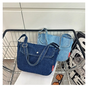 Detailed view of vintage canvas crossbody bags in blue denim with red logo and wide straps