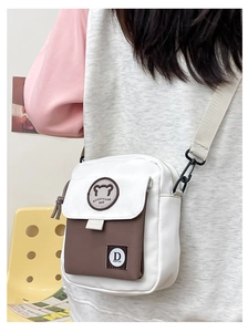 Detail view of the cute bear logo and color-block canvas crossbody bag for women