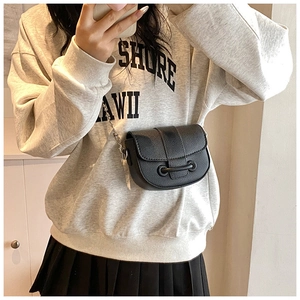 Close-up of black PU leather mini saddle bag with metal chain strap on a model