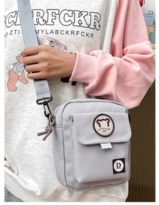 Close-up of light gray canvas crossbody bag with cute bear patch and adjustable strap