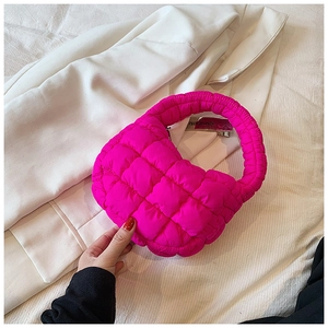 Detailed macro view of the bright pink quilted puffer cloud bag on white suit fabric