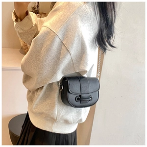 Detailed view of black lychee grain leather saddle bag with silver chain strap and buckle