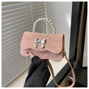 Close-up of pink marble pattern bag with metallic bow detail and pearl handle strap