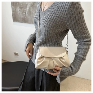 Détail du sac nuage plissé beige avec bandoulière chaîne sur pull gris chiné