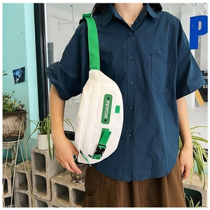 Detail view of white canvas chest bag with bright green strap and WOAINI branding
