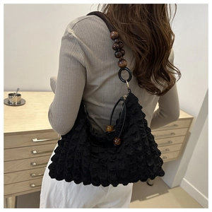 Detail of black textured bubble fabric shoulder bag with wooden bead strap and drawstring