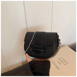Detail shot of black litchi texture saddle bag with elegant silver ball chain strap