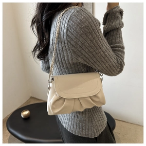 Sac nuage beige chic avec bandoulière chaîne argentée porté par un mannequin en studio