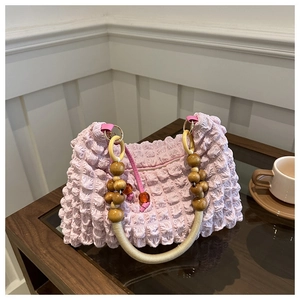 Detail view of pink bubble fabric bag with wooden bead handle on a wooden table