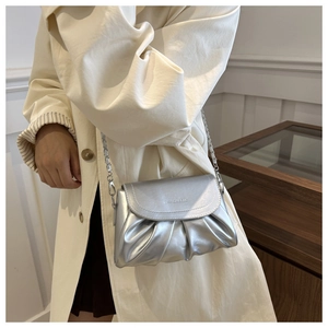 Gros plan sur le sac nuage plissé argenté avec bandoulière chaîne sur un manteau beige