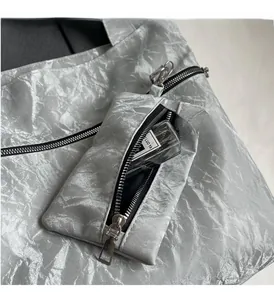 Close-up of silver tote bag with textured metallic finish and small zipper pouch