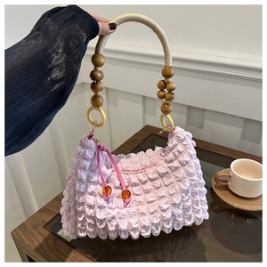 Detail of pink pleated fabric tote with wood bead handle and decorative amber beads