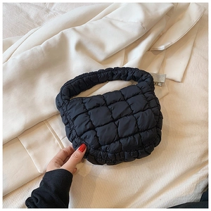 Detail view of black quilted puff bag with 3D texture and integrated top handle