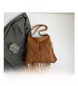 Detail view of brown faux leather bag featuring long fringe and metallic rivets design