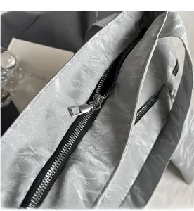 Close-up of smooth silver metal zipper on silver-grey tote bag with pleated texture
