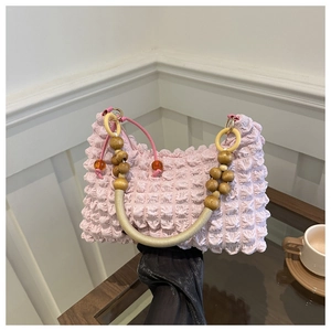 Detail of pink bubble texture bag with decorative wooden bead handle and orange accents
