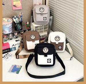 Detail view showing four colors of mini canvas crossbody bags with cute bear logo and flap