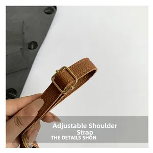 Detail of brown leather adjustable shoulder strap with gold buckle and lychee texture