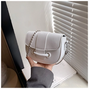 Close-up of white pebble leather mini saddle bag with silver bead chain and metal ring handle