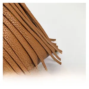 Close-up of the textured brown leather fabric and fringe tassel detail on this tote bag