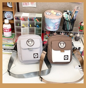 Detail of small bear canvas crossbody bags in grey and brown colors with adjustable straps