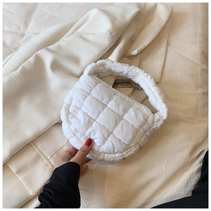 Detailed macro view of white quilted bubble fabric and ruched handle on a cloud bag